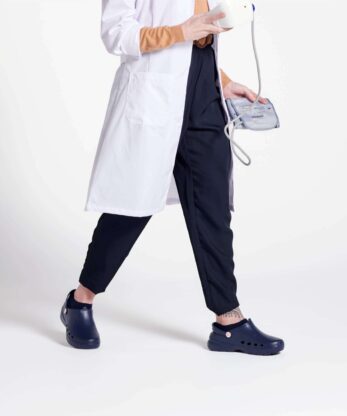 Una mujer con bata de laboratorio sosteniendo una taza y un estetoscopio, llevando calcetines de hospital Wock Waylite.