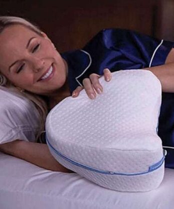 Una mujer tumbada en la cama con un cojín ortopédico para las piernas.