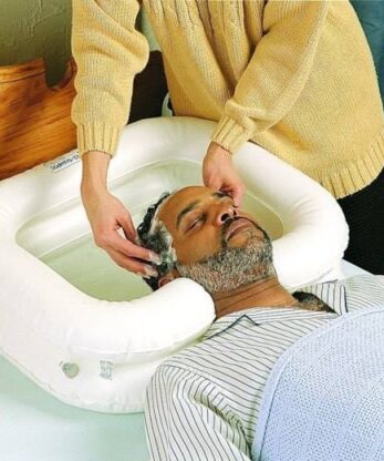 Descripción: Un hombre recibe un masaje craneal en una bandeja hinchable para lavarse la cabeza.