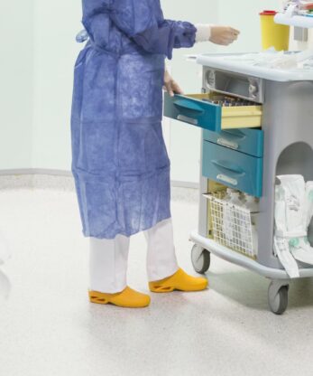 Una mujer con uniforme azul junto a un carro sanitario Socas WOCK Bloc.