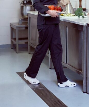 Une femme transportant un plateau d'aliments Socas WOCK Everlite Plus dans une cuisine.