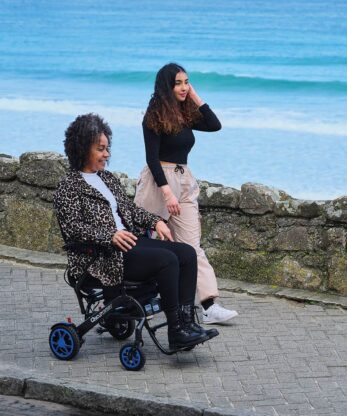 Una mujer en una silla de ruedas eléctrica Q50r Carbon junto al océano.