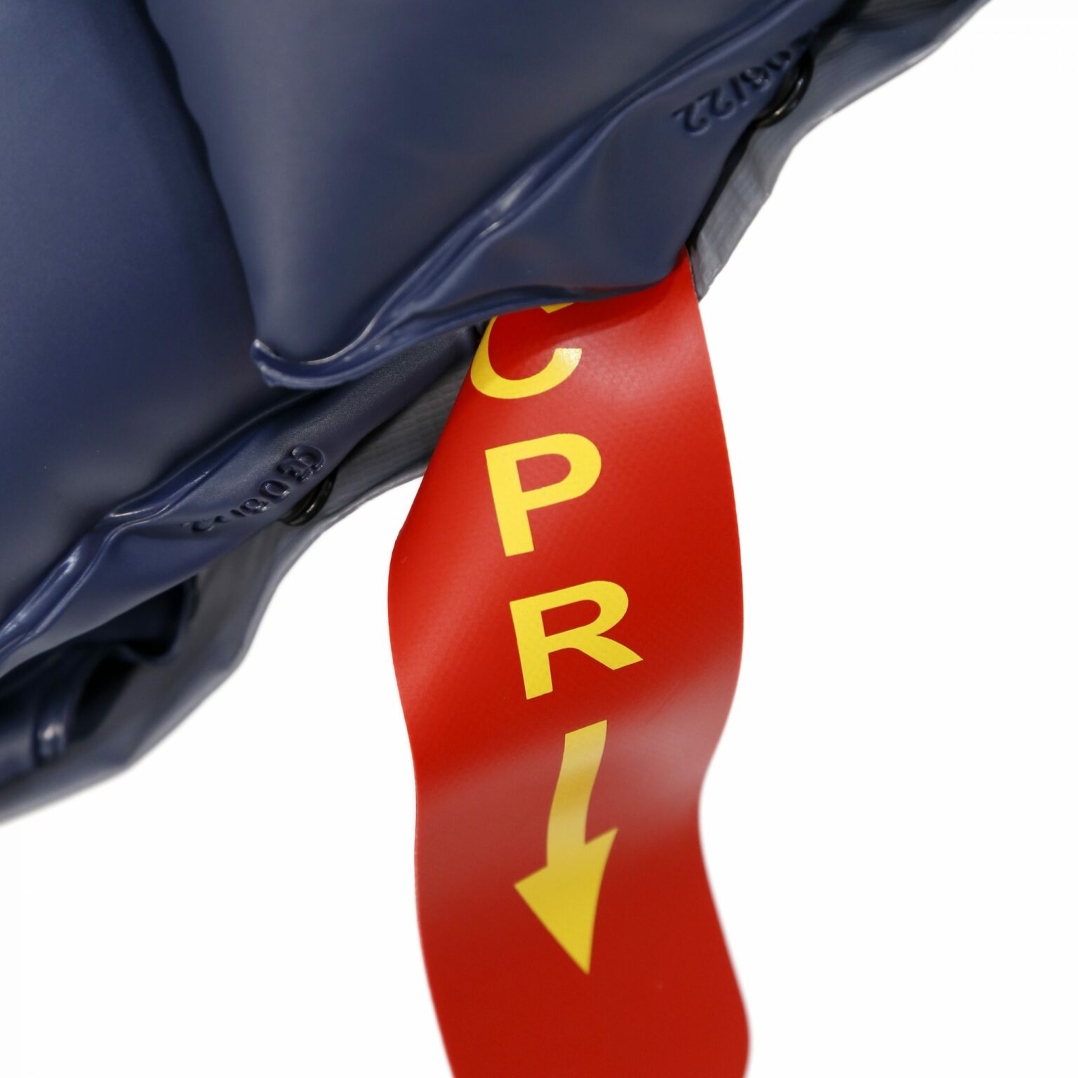 Primer plano de una etiqueta roja con las letras "CPR" y una flecha hacia abajo en amarillo, adherida a un compresor tubular antidecúbito de color azul oscuro.