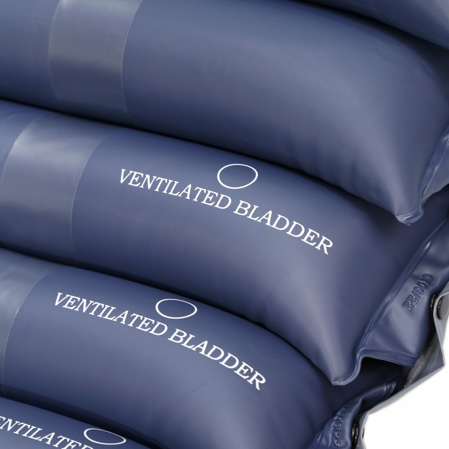 Close de bolsas de ar azul-escuras empilhadas, rotuladas como "Bexiga Ventilada", usadas no Colchão Tubular Anti decúbito com Sistemas compressores projetados para terapia anti decúbito.