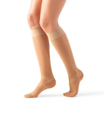 Une personne portant des chaussettes de compression au niveau du genou Lycra Rest Socks AD 140 DEN de couleur nude, debout, les pieds légèrement écartés, sur un fond blanc uni.