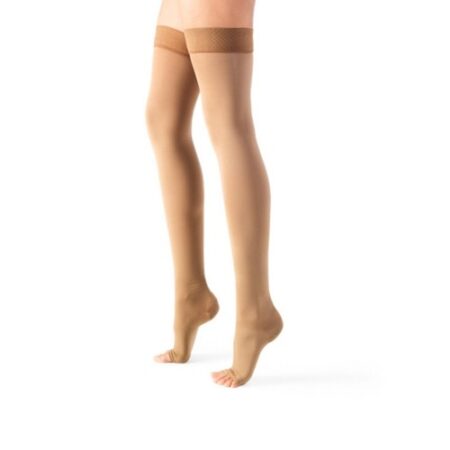 A person wearing Lycra AG Class II thigh-high compression stockings from Meias Terapêuticas in beige, standing against a white background.