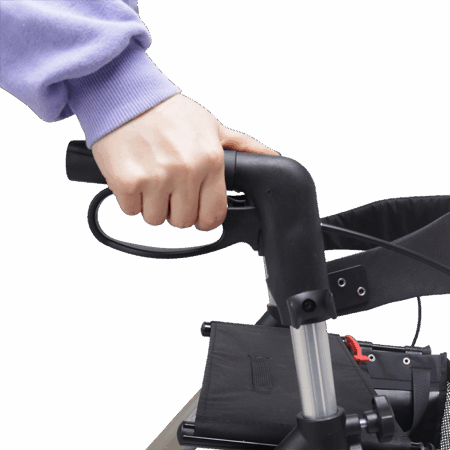A person wearing a purple sleeve holds the handle of a black Rollator Stylus mobility aid.